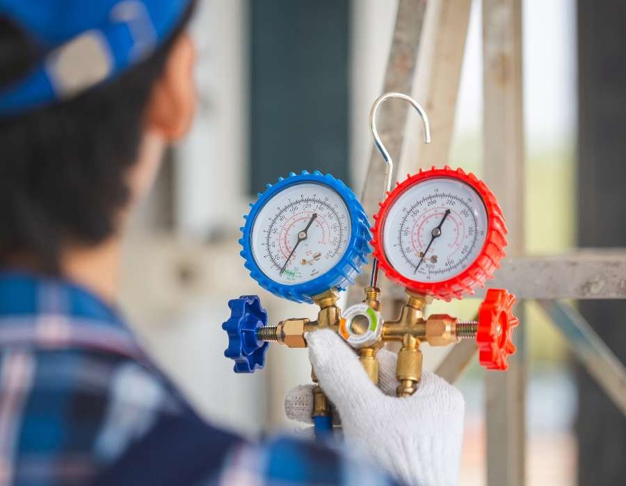 Technician checking refrigerant gauge readings